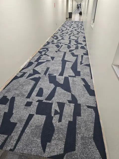 Navy and gray abstract-pattern carpet tile installed in a long commercial corridor