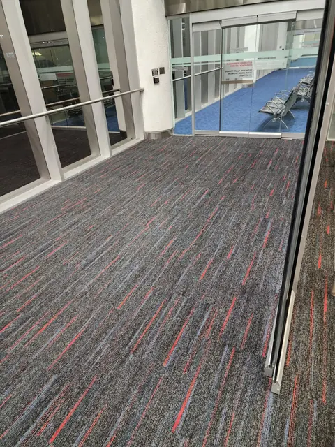 Long run of new carpet tile beside a glass partition at Miami International Airport