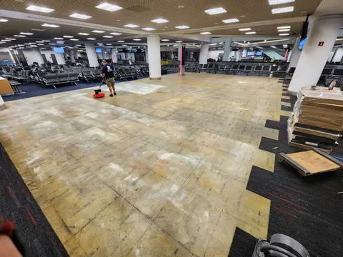 Installer preparing the substrate with a floor machine at Miami International Airport