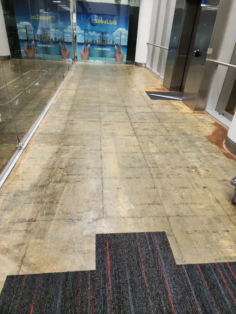 Carpet tile installation starting on a prepared airport corridor floor